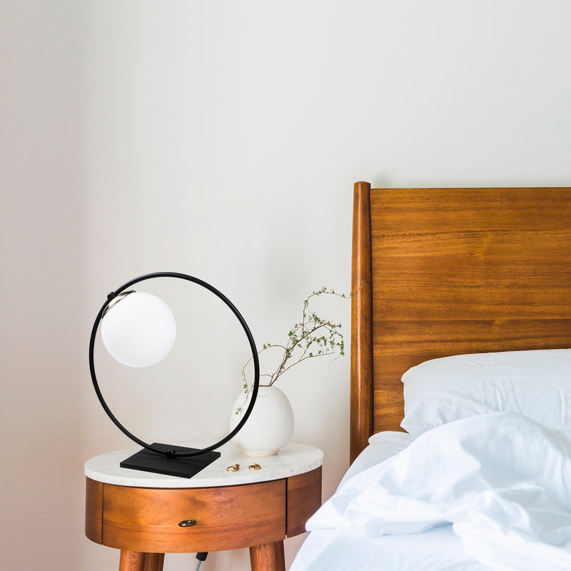 lampada da comodino moderna con cerchio in metallo nero e paralume a sfera in vetro bianco