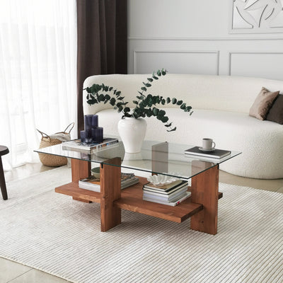 Tavolino basso da soggiorno in stile moderno, design rettangolare a due piani. Struttura in legno massello color noce opaco dai toni caldi e ripiano superiore in vetro temperato trasparente. Dimensioni cm 105x60x40h